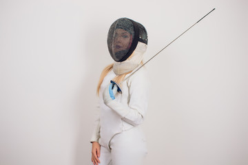woman wearing fencing suit practicing with sword against grey vignette