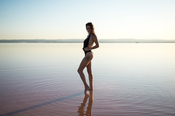 Fototapeta na wymiar Young girl in black swimsuit at the beach