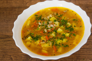 Fish soup with potato and rice on a wooden background.