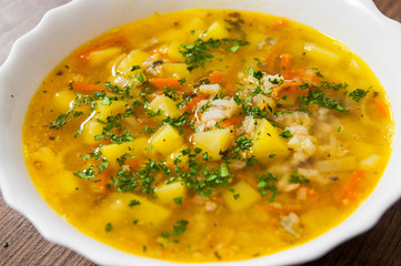 Fish soup with potato and rice on a wooden background.