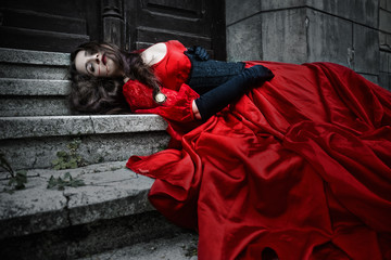Lying and bleeding woman in a red Victorian dress - 180235383