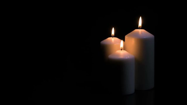 Three white candles burning on black background. 4k shot at 60 fps.