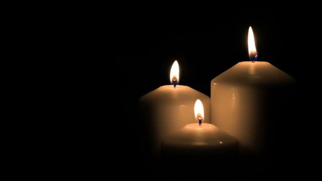 Three white candles burning on black background. 4k 