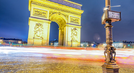 Traffic around Triumph Arc at night in Paris - France