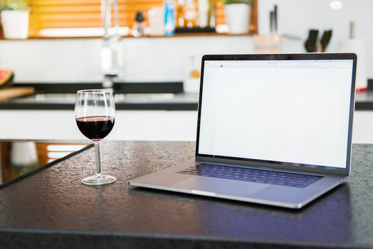 Laptop in the kitchen with a wine glass