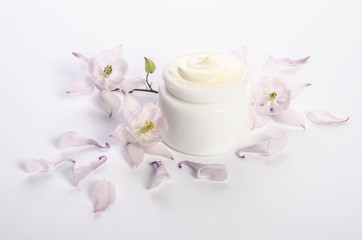Cute flowers and petals and a jar of natural body cream isolated on white background