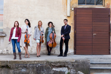 Obraz na płótnie Canvas Five-person musical band, stand outdoor close a wooden door