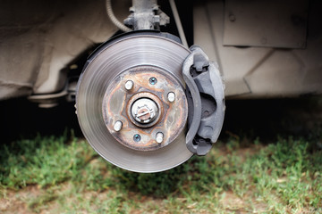 Broken rusty brake discs on the car on the Jack. Steel brake pads