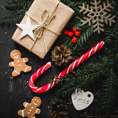 Christmas background with gingerbread, xmas tree and decoration on dark wooden board.