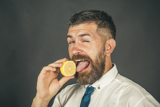 man with long beard lick lemon fruit on black background