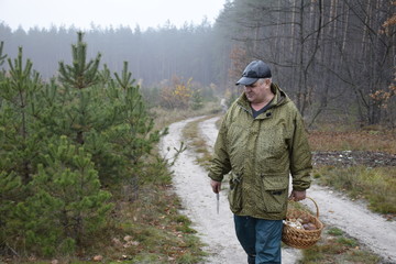 мужчина идет по проселочной дороге с корзиной грибов   © sashasandro