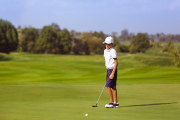 Boy golf player practicing at green, disappointed after fail shot