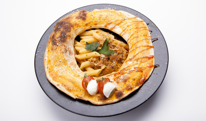 Pasta with meat, tomato sauce and vegetables in black plate,isolated