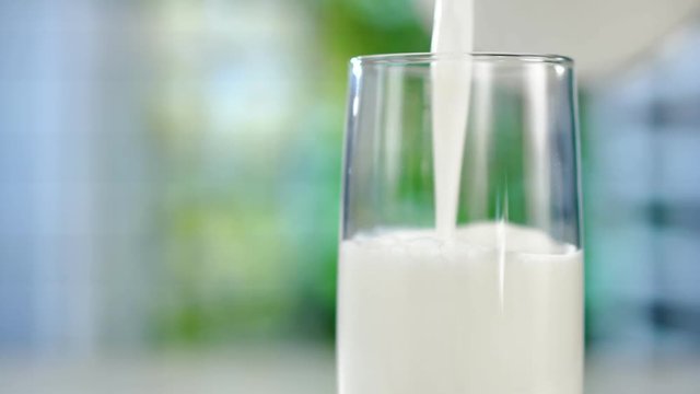 Close-up pouring fresh milk from the jug on table