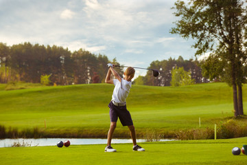 Obraz premium Boy golf player hitting by iron from fairway at golf course