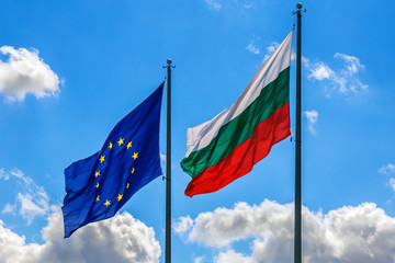 The national flags of Bulgaria and the European Union on the background of blue sky with clouds.