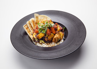 Fried chicken fillet, boiled potatoes and vegetables in black plate,isolated