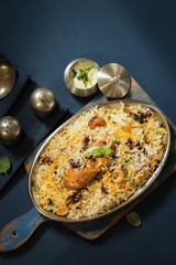 Homemade Chicken Dum Biryani served with raita, Overhead view on dark blue background