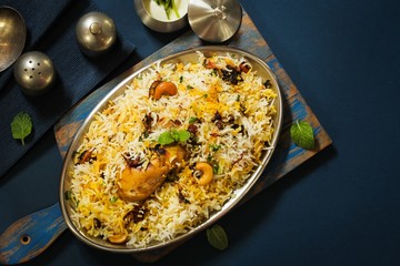 Homemade Chicken Dum Biryani served with raita, Overhead view on dark blue background