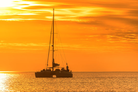 Catamaran glides at twilight on water surface of the baltic sea. Sailing into the golden sun