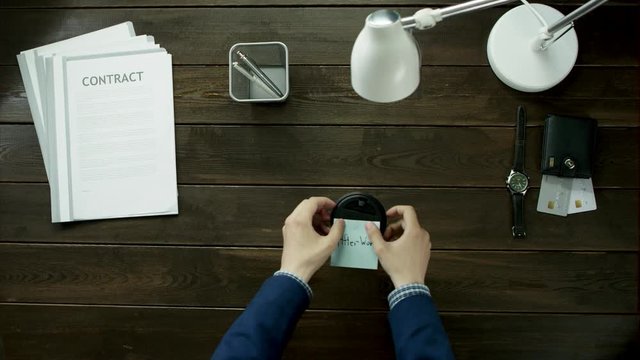 Man glues a sticker on a glass of coffee with text after work.