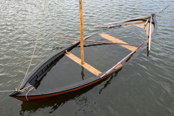 Wooden sailboat on the sea, water inside. Boat under water.