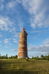 Lighthouse and house in the Baltic Sea. Shore, evening light, sunset, clouds and architecture concept. Mohni, small island in Estonia, Europe.