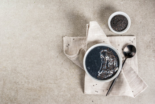 Trendy vegan food recipes, Black Sesame Soup with sesame seeds and coconut milk, grey stone table, copy space top view