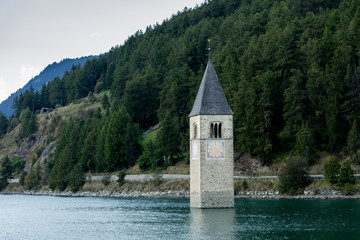 Church under water, drowned village, mountains landscape and peaks in background. Reschensee Lake Reschen Lago di Resia. Italy, Europe, Südtirol, South Tyrol, Upper Adige, Alto Adige