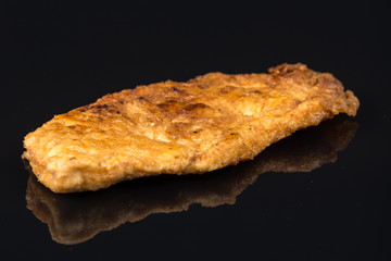 Fried breaded chicken white meat breasts in eggs above black background table with reflections and copy space
