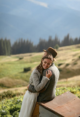 Fototapeta premium Newlyweds stand, smile and hug on background of mountains.
