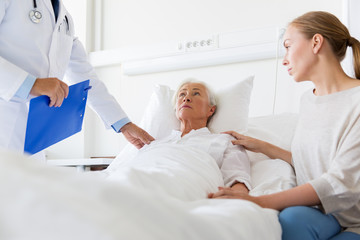 Fototapeta premium senior woman and doctor with clipboard at hospital