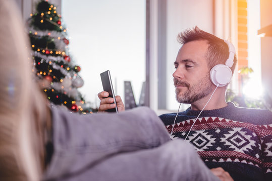 Men listening music at home with feet up at desk