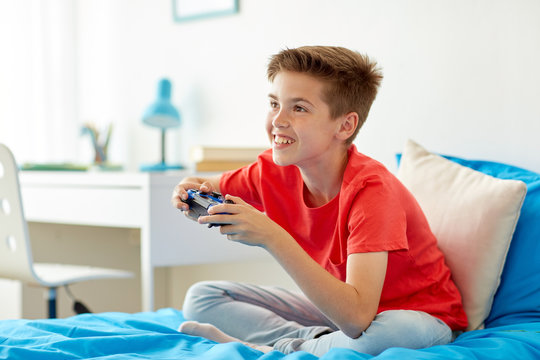 happy boy with gamepad playing video game at home