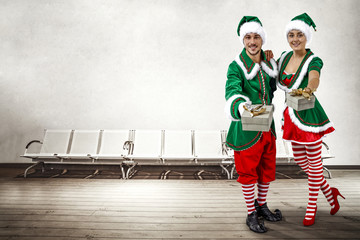 Two Christmas elves in the waiting room. a large wooden floor, white chairs and a white wall with space for your inscription. Christmas advertising background.