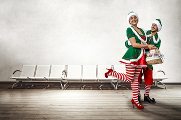 Two Christmas elves in the waiting room. a large wooden floor, white chairs and a white wall with...