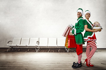 Two Christmas elves in the waiting room. a large wooden floor, white chairs and a white wall with...