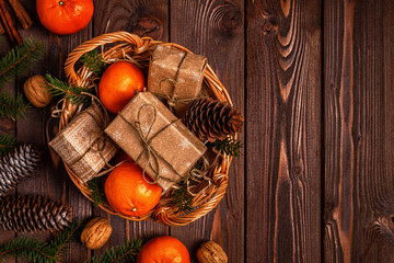 Christmas composition with tangerines, gift boxes, cones on a dark wooden background.