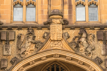 Sydney, Australia - March 25, 2017: Closeup of brown stone detail of historic Nicholson Museum facade above entrance with emblems, lion, horse, monster.