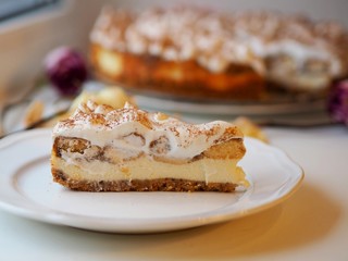 Cheesecake tiramisu with Savoiardi biscuits and cream with cocoa, in the background there is rose