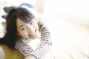 床に寝転びくつろぐ笑顔の10代女性