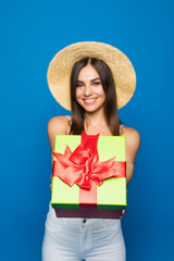 Happy woman hold red gift box with smile isolated on blue background pointed on you