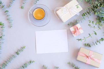 Green leaves with gift boxes with coffee on blue table from above with copy space on paper note , flat lay scene