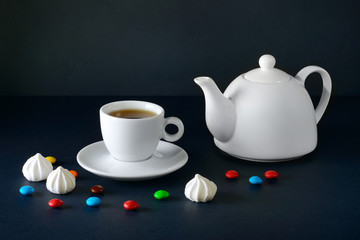 White cup and tea pot on a black background.