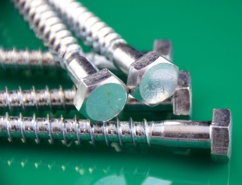 &Uuml;berbelichtet und mit gr&uuml;n reflektierendenm Hindergrund silber schimmernede Sechskantschrauben