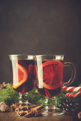 Traditional christmas warm drink mulled wine in glasses on wooden background with pine branches.