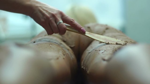 The cosmetics mud therapy for the body. The woman is laying while the doctor is putting the mud on.