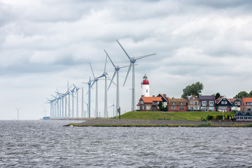 Seascape Dutch fishing village Urk with big wind turbines raising above the skyline of the houses - obrazy, fototapety, plakaty