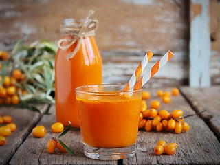 Homemade buckthorn soft drink in a glass and ripe sea buckthorn berries on the table. Healthy and...