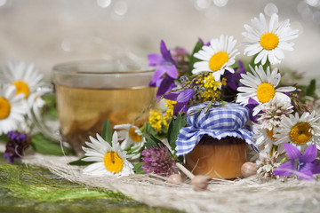 Чашка чая, мед и букет полевых цветов.